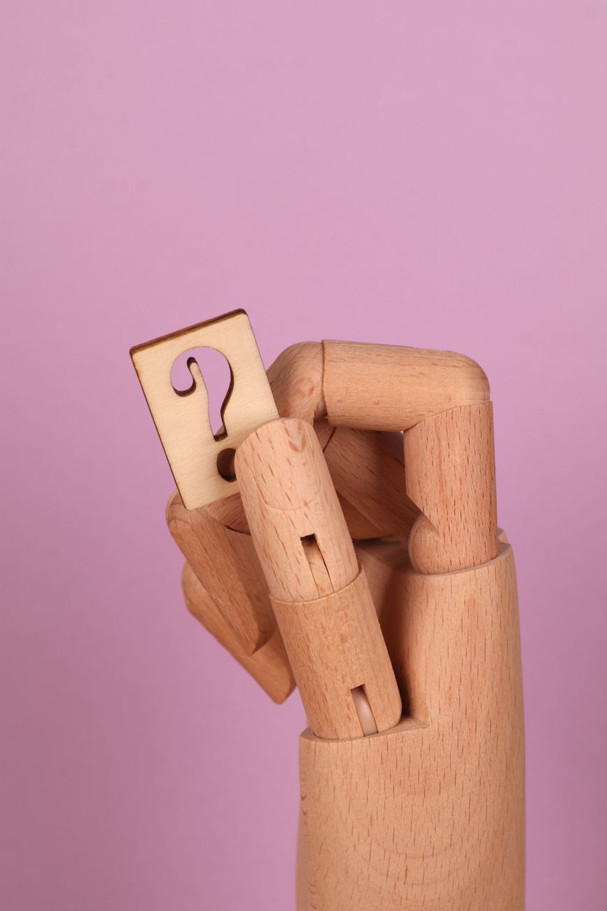 wooden hand holding a wooden question mark