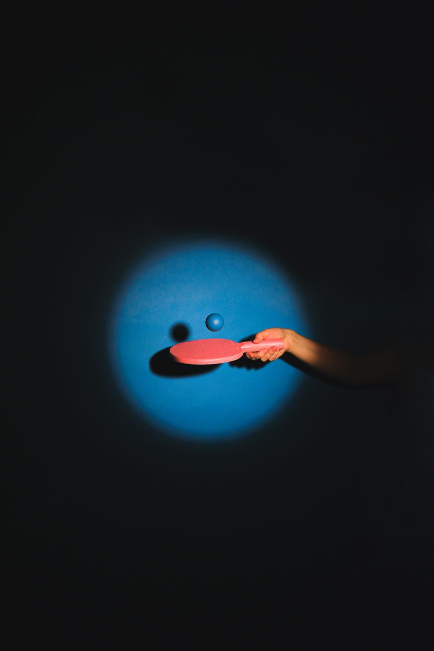 a person bouncing a ball on a ping pong paddle