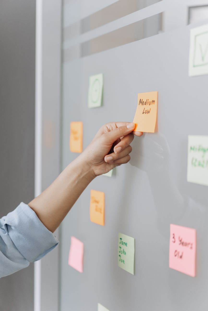 a hand holding the orange sticky note on the glass wall